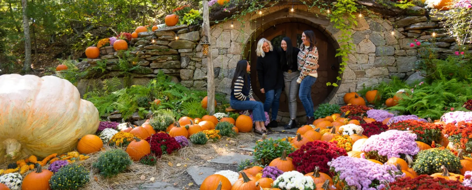 Group of women at The Preserve's Hobbit House surrounded by pumpkins and fall flowers