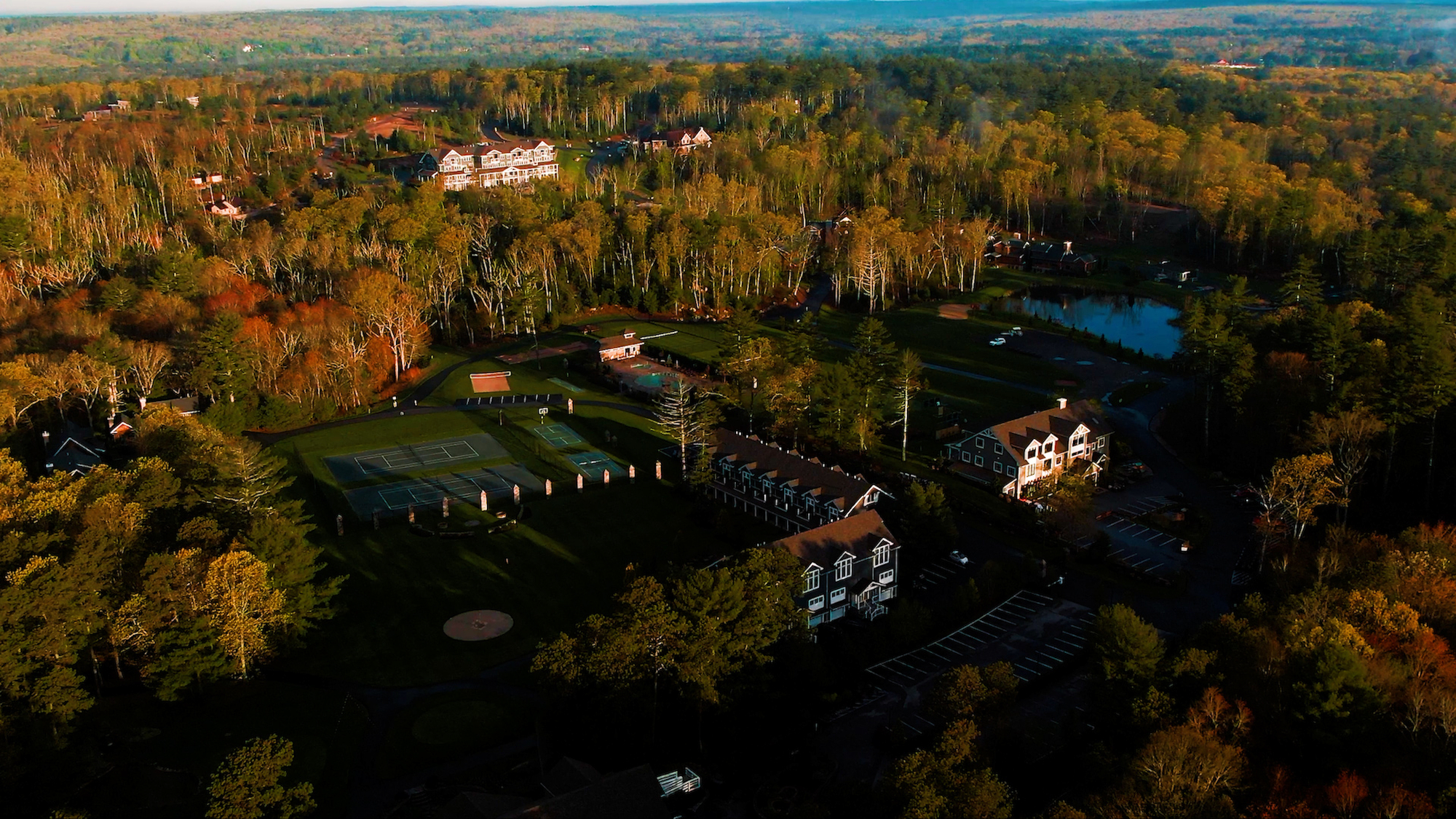 This is an aerial view of a large estate with buildings, tennis courts, and surrounding forest.

