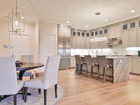 Modern kitchen with island, bar stools, and dining area with stylish chairs.