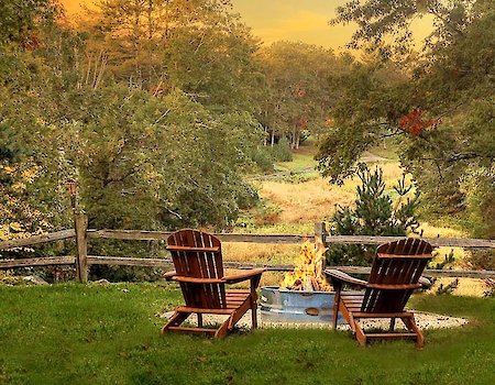 Cozy fire pit with chairs overlooking New England wilderness