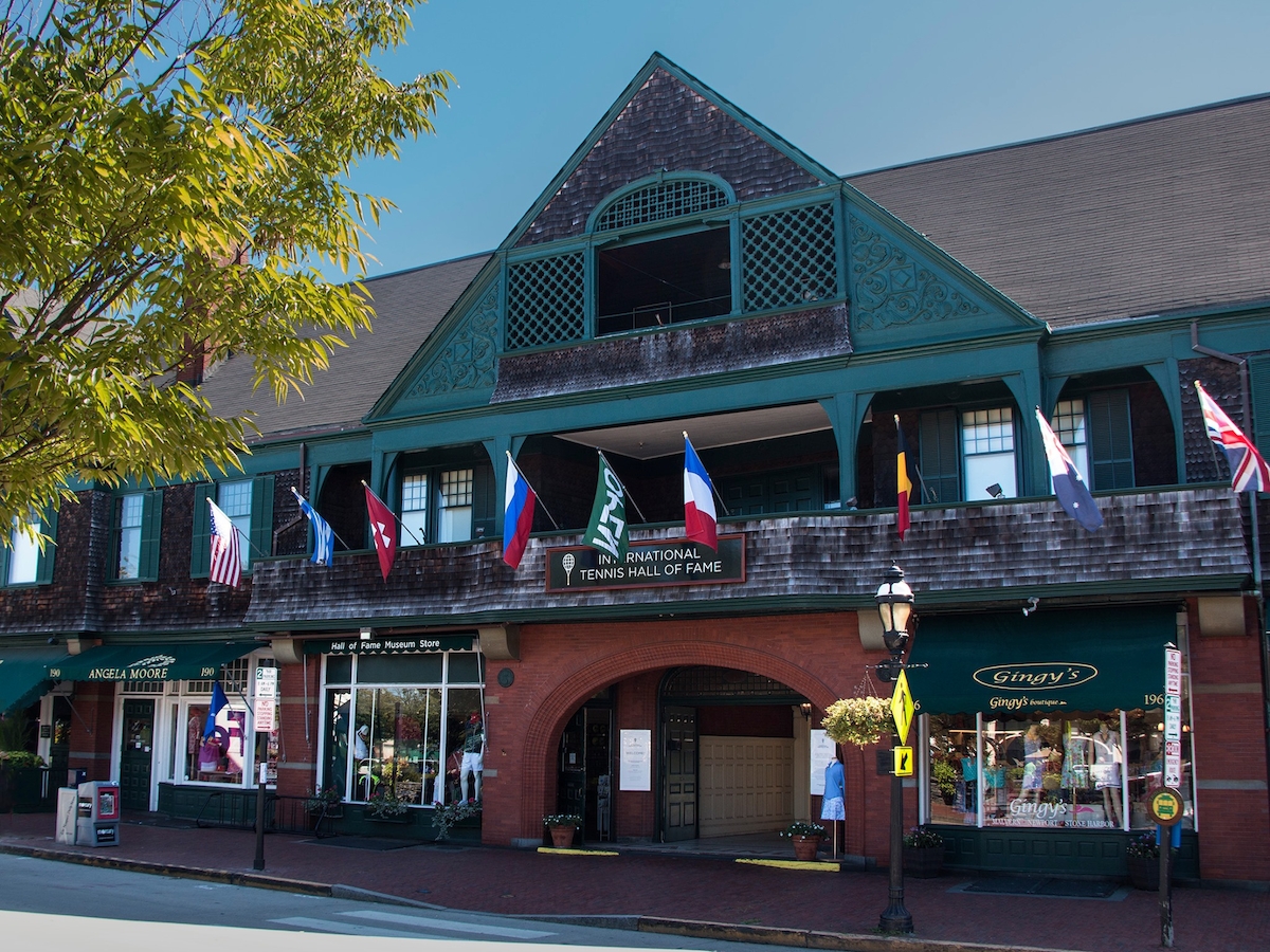 The image shows a brick building featuring multiple international flags and shops on the ground floor, one labeled 