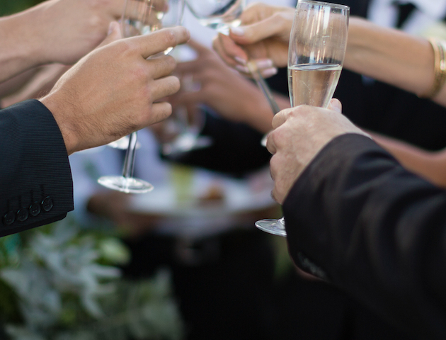 A group of people toasting with champagne glasses at a celebration, with a chilled bottle in an ice bucket nearby.